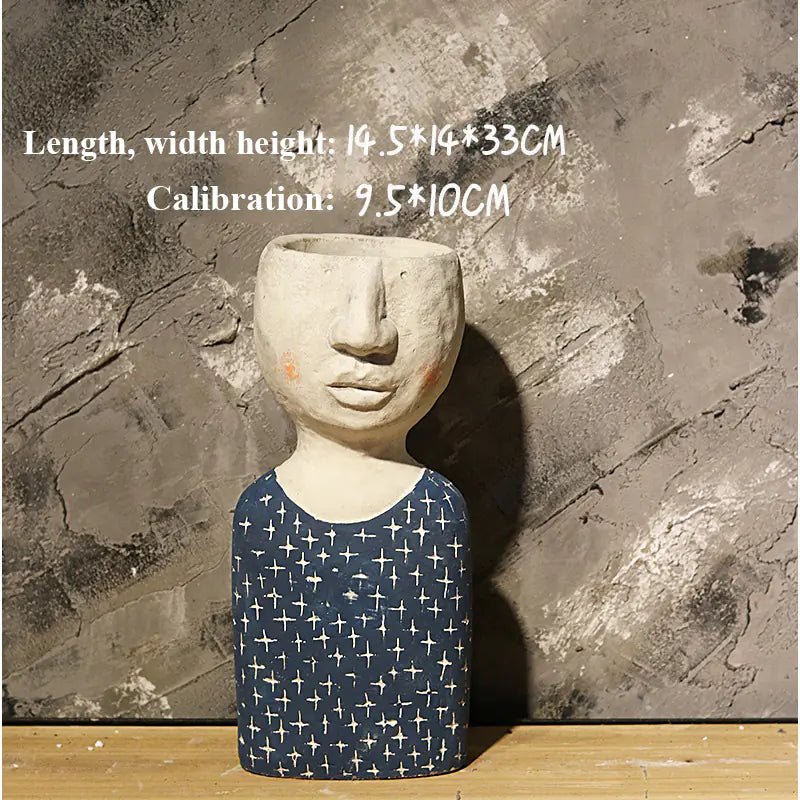 Ceramic sculpture with face and patterned body against a textured stone wall