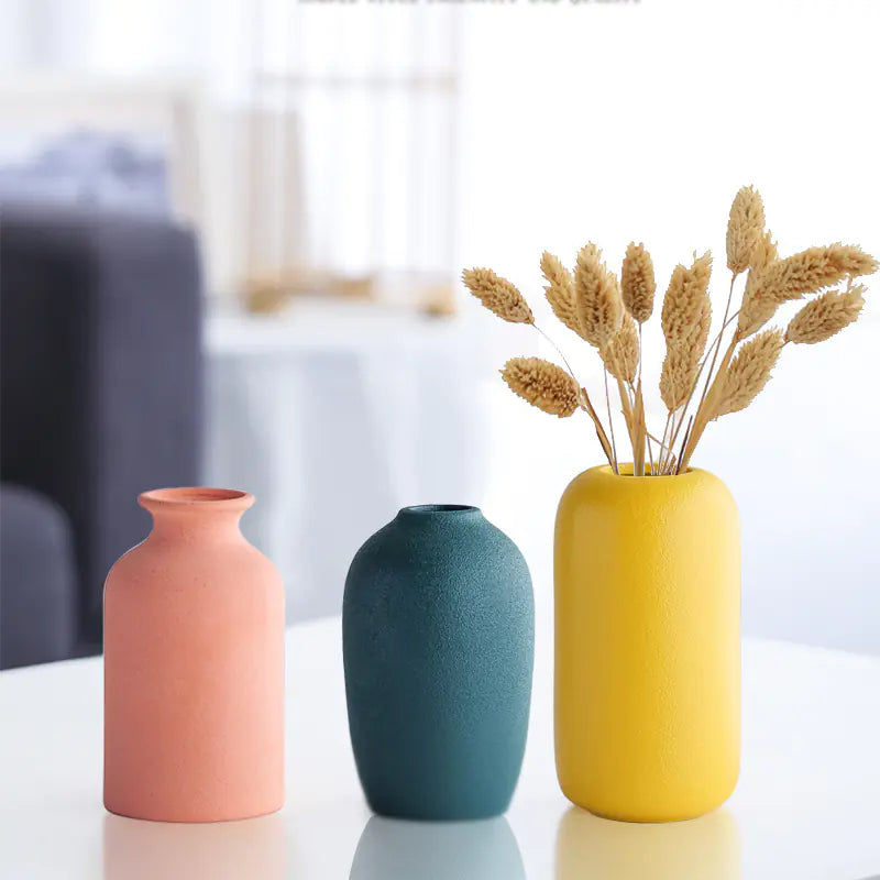 Three colorful vases on a reflective surface with a blurred background