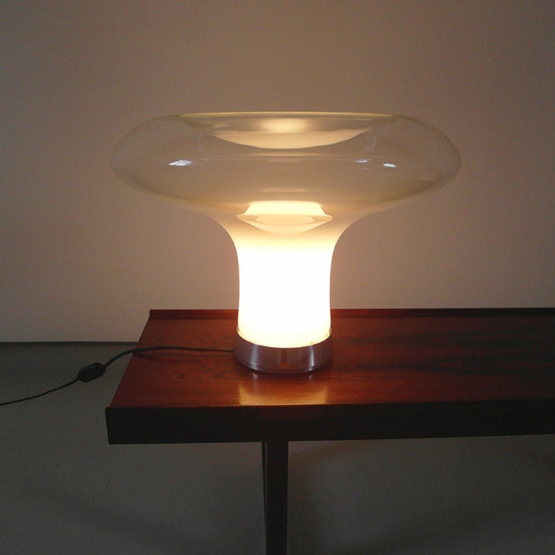 Modern table lamp with a glass shade on a wooden table against a plain wall.