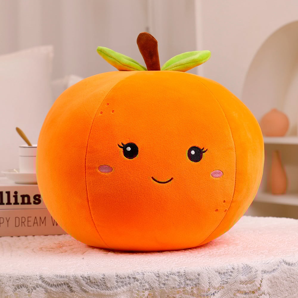 Plush pumpkin pillow with a face on a soft surface