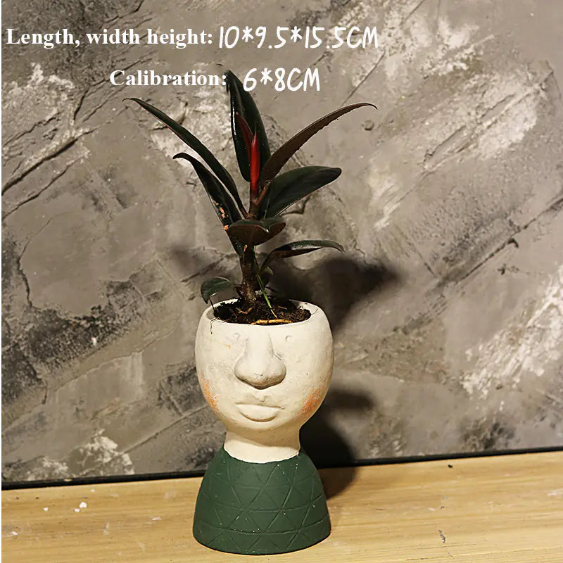 Ceramic face-shaped planter with a plant on a wooden surface against a stone wall background