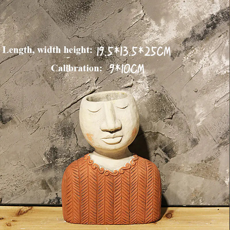 Ceramic planter shaped like a face with a sweater on a stone surface