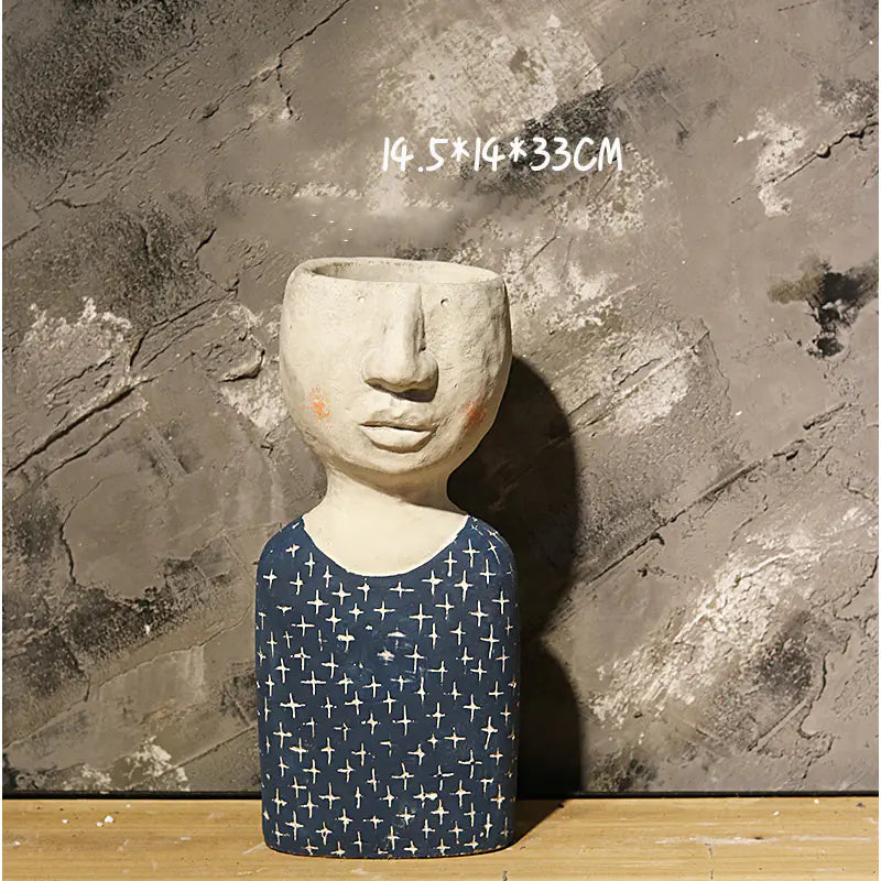 Ceramic sculpture with face and patterned body against a textured wall