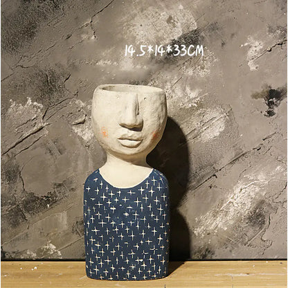 Ceramic sculpture with face and patterned body against a textured wall