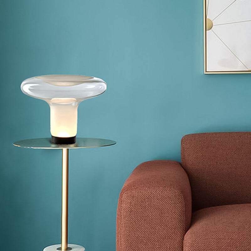 Modern side table with a lamp next to a brown sofa against a teal wall.