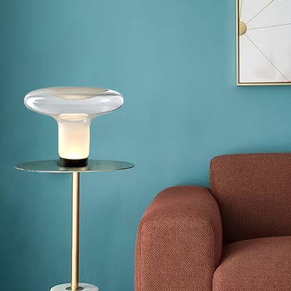 Modern side table with a lamp next to a brown sofa against a teal wall.