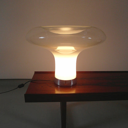 Modern table lamp with a glass shade on a wooden table against a plain wall.