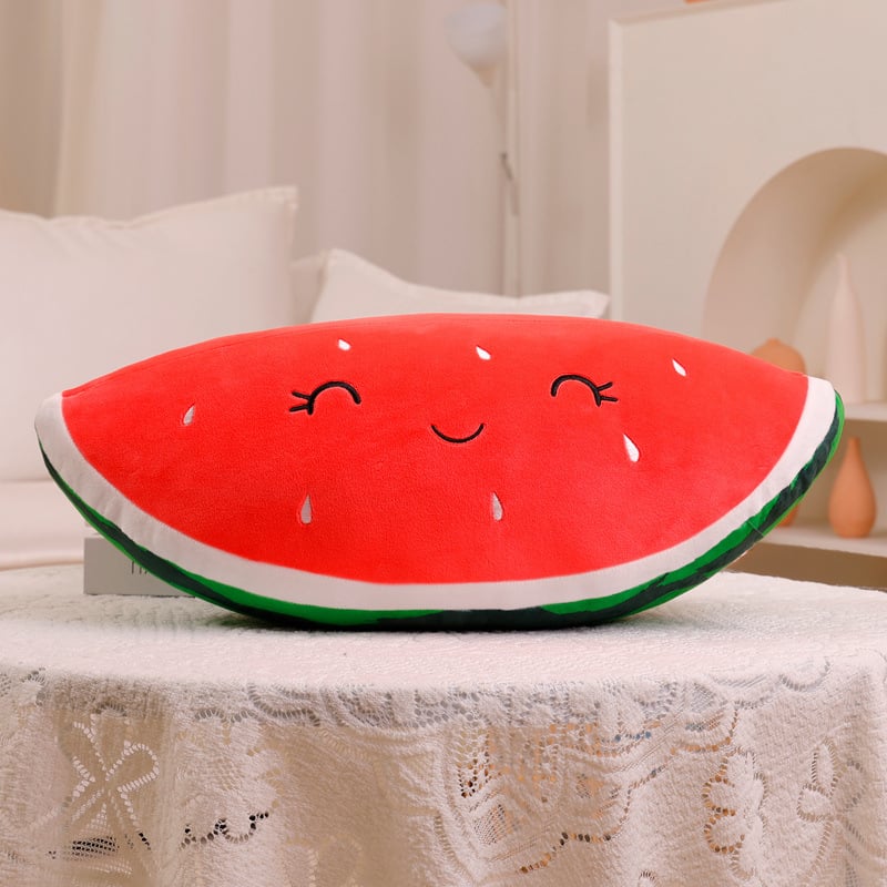 Watermelon-shaped pillow with a smiley face on a table